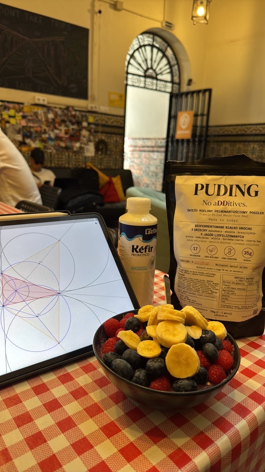 PUDING na stole w coworkingu z kefirem, owocami i tabletem